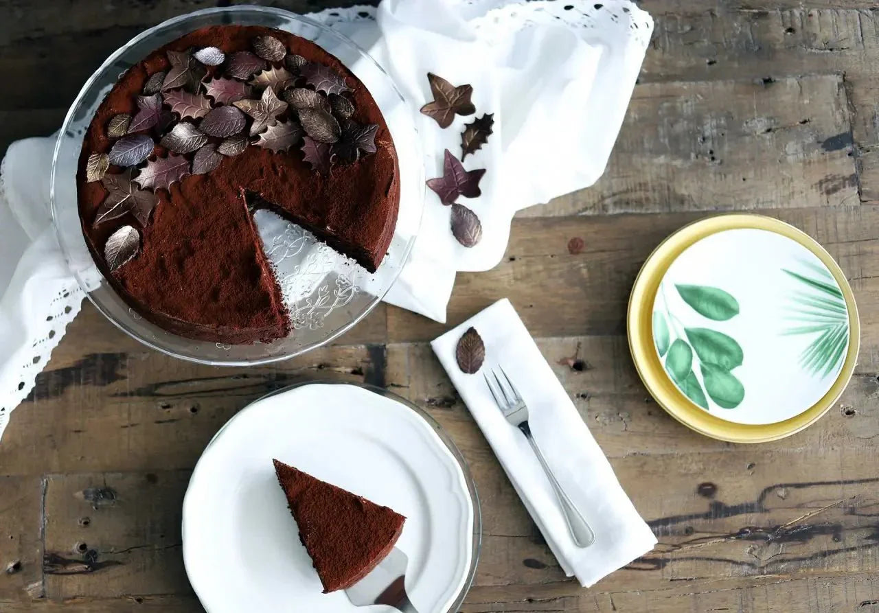 Glutenfreier Schokoladen-Orangen-Fudge-Cake mit Schokoladenblättern, serviert auf Holzuntergrund.