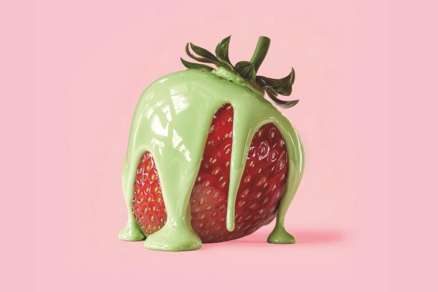 Erdbeere mit grüner Matcha-Glasur auf rosa Hintergrund, herabtropfend und appetitlich inszeniert.