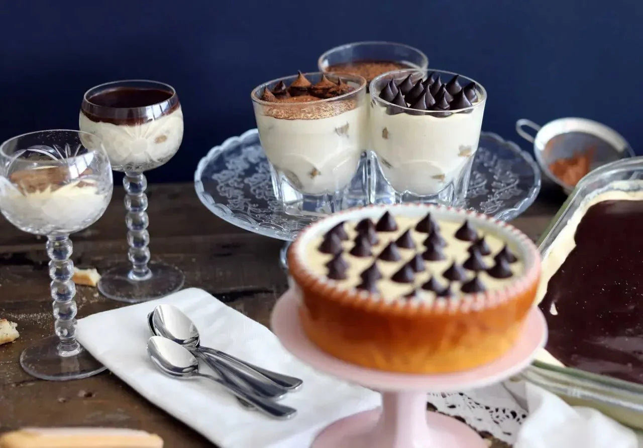 Tiramisu mit Edelkakao-Schokolade in Gläsern und auf einem Tortenteller, dekoriert mit Schokospitzen.