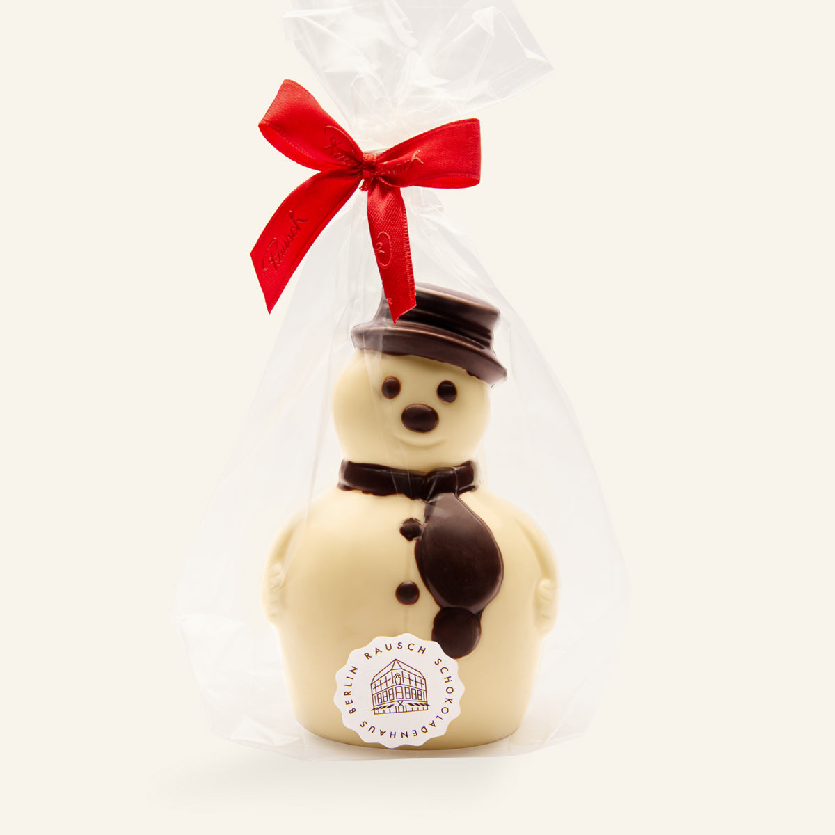 Handwerkliche weiße Schokoladen-Schneemannfigur mit braunem Hut und Schal, verpackt mit roter Schleife. - Rausch