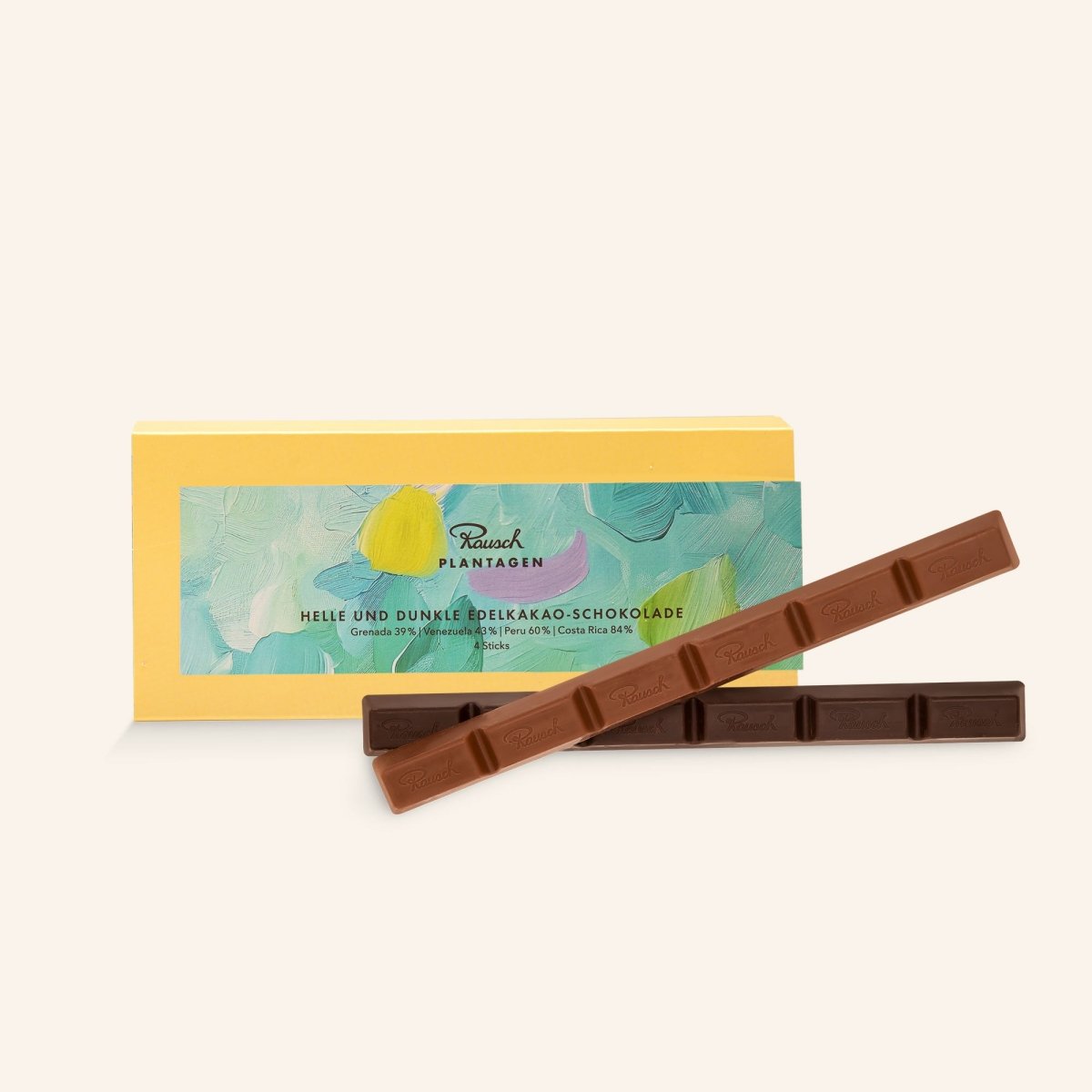 Gelbe Verpackung mit verschiedenfarbigen fröhlichen türkisen Pinselstrich-Mustern. Im Vordergrund zwei Rausch Plantagen Sticks aus heller und dunkler Edelkakao-Schokolade.