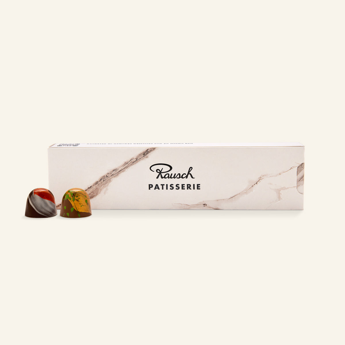 Elegante weiße Pralinenbox mit Marmoroptik und zwei handwerklichen Pralinen in Rot- und Gelbtönen. - Rausch