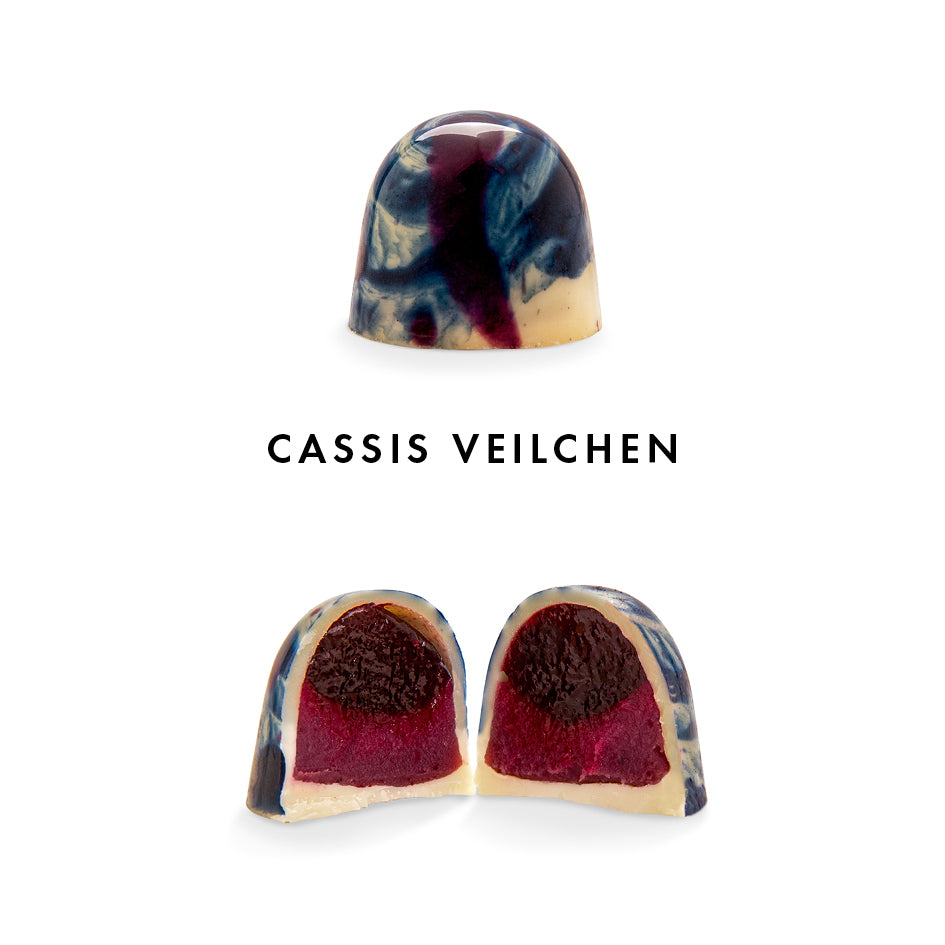 Handwerkliche Praline mit marmorierter blauer und weißer Schokolade, Fruchtfüllung innen sichtbar. - Rausch