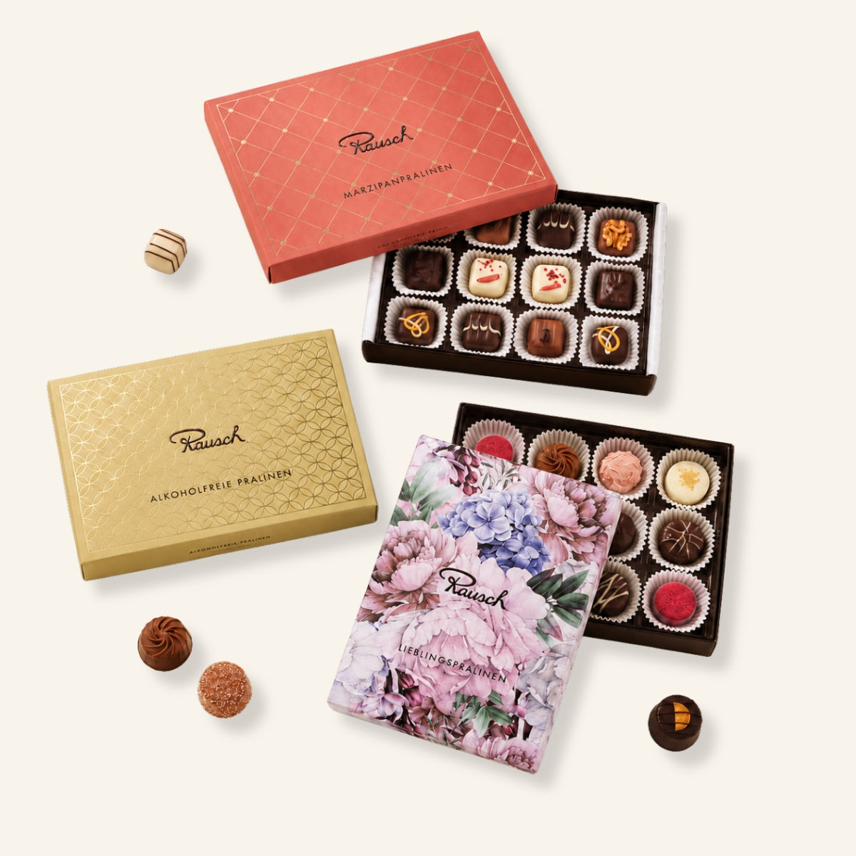 Drei Pralinen-Sets mit handwerklicher Schokolade, edle Verpackungen in Rot, Gold und floralem Design. - Rausch