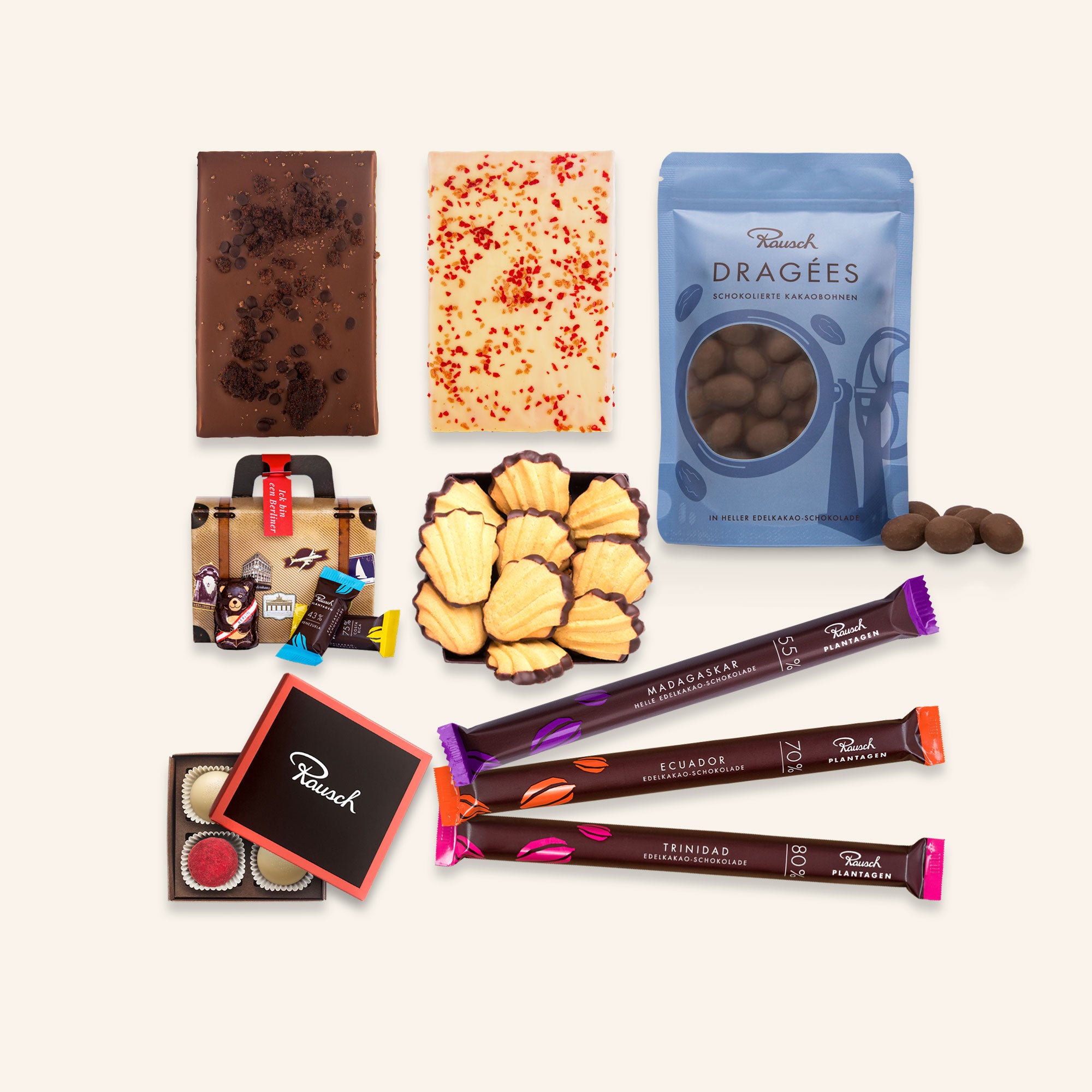 Inhalte des exklusiven Schokoladenabos. Zwei verfeinerte Tafeln, Kakaobohnen-Dragées, Bärentatzen, Berliner Koffer, 4er Pralinenschachtel und drei Sorten Rausch Plantagen Sticks.