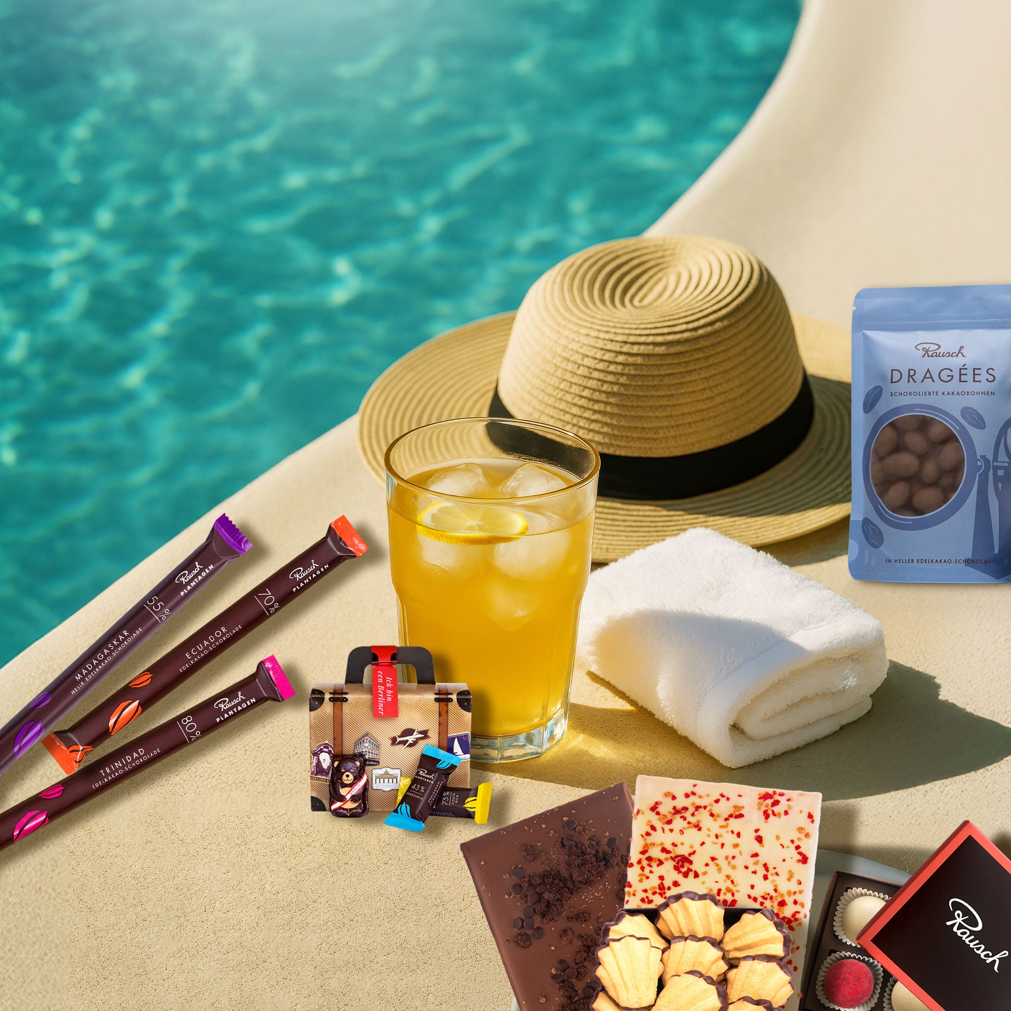 Sommerliches Motiv am Pool mit Sonnenhut, Handtuch und Erfrischungsgetränk. Dazu die Inhalte des Schokoladen-Abos No. 4