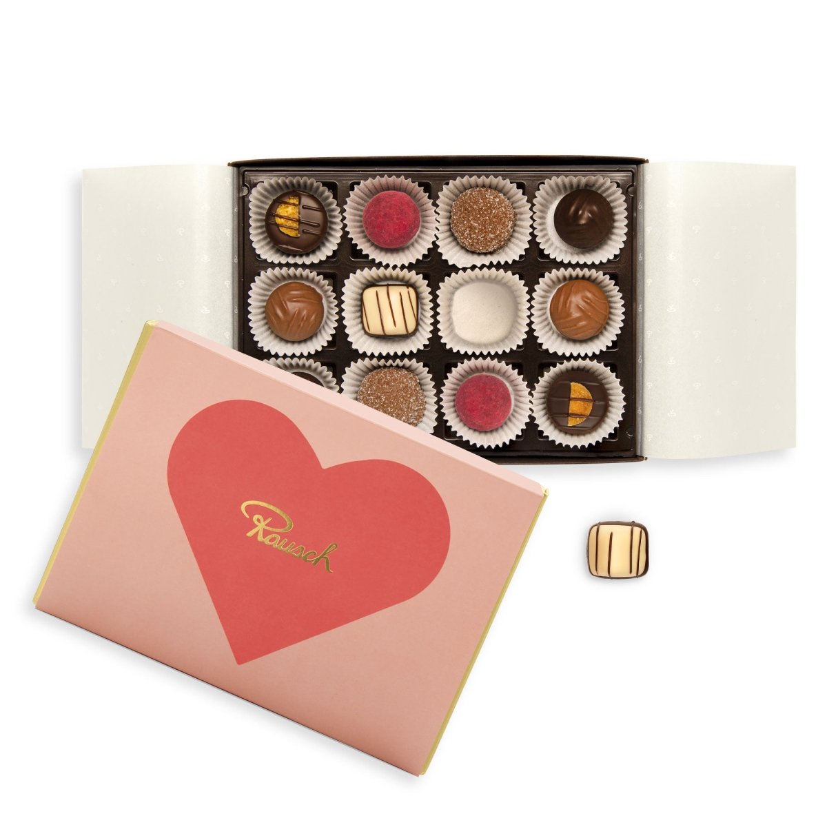 Pralinenschachtel mit Herzmotiv geöffnet auf weißem Hintergrund. Es kommen verschiedene Pralinensorten zum Vorschein.