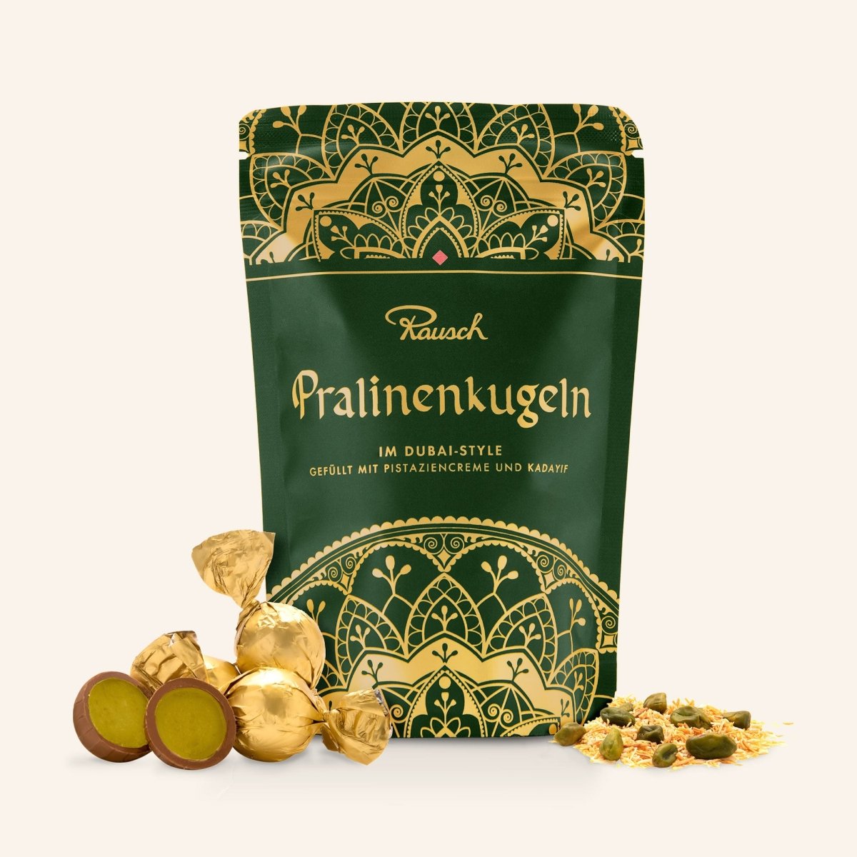 Grün und gold verzierte Verpackung mit Dubai-Style Pralinenkugeln. Im Vordergrund liegen einzelne Pralinenkugeln, Pistazien und Kadayif.