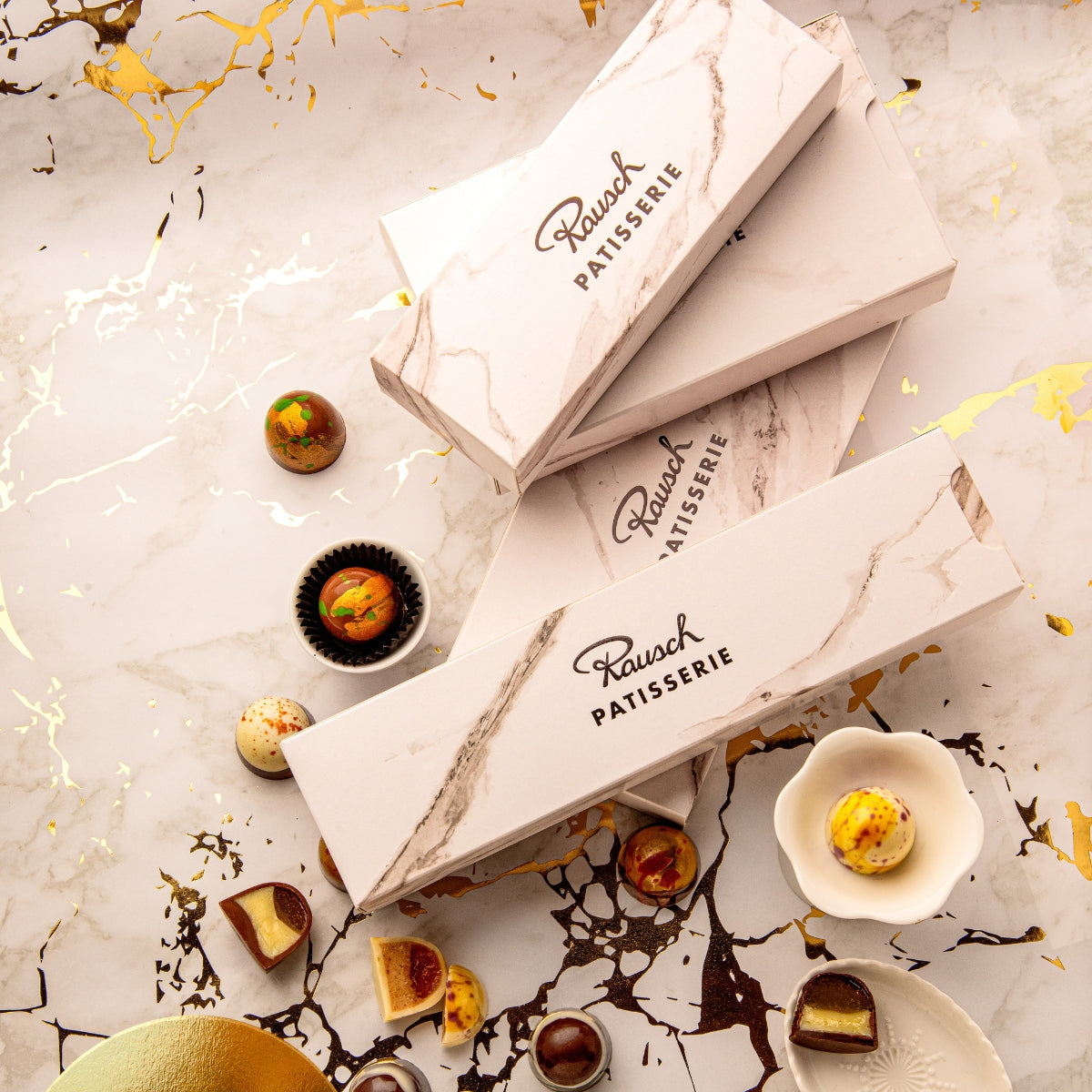 Geöffnete Box mit handgemachten Patisserie Pralinen in Rot-, Gelb- und Brauntönen. - Rausch