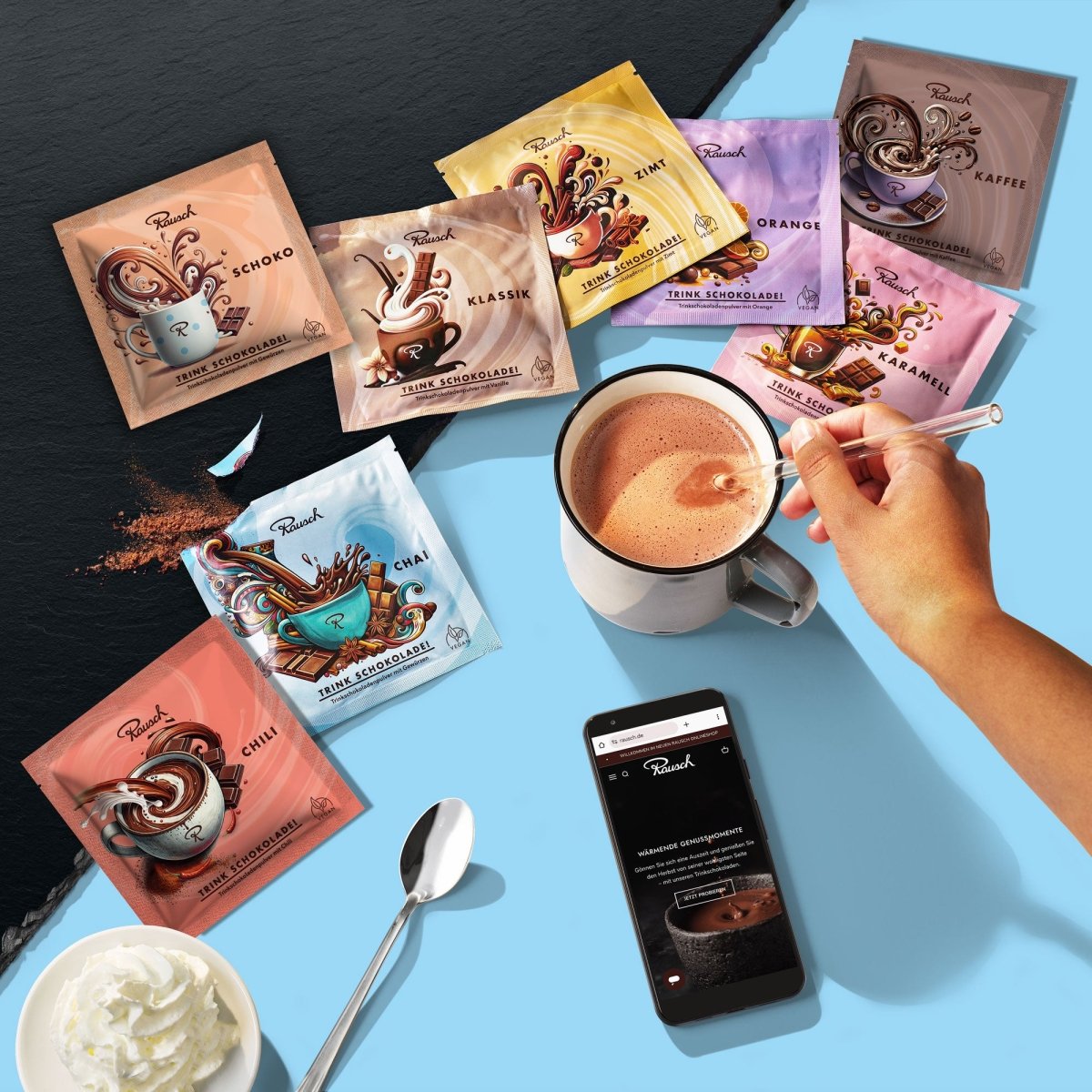 Acht verschiedene Trinkschokoladen-Sorten in verschiedenfarbigen Sachets, eine Hand rührt eine Tasse Schokolade um, daneben Smartphone, Sahne und Löffel.
