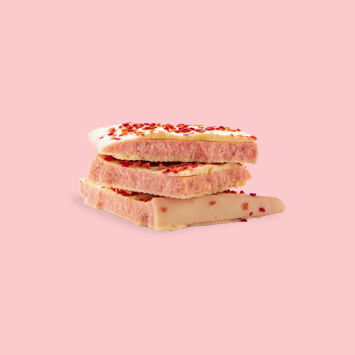 Weiße Schokoladentafel mit kleinen Erdbeer- und Himbeerstückchen, im Anschnitt kommt die rosa Erdbeer-Füllung zum Vorschein. 